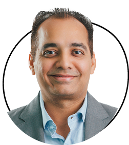 Person smiling, wearing a suit and shirt, facing forward.