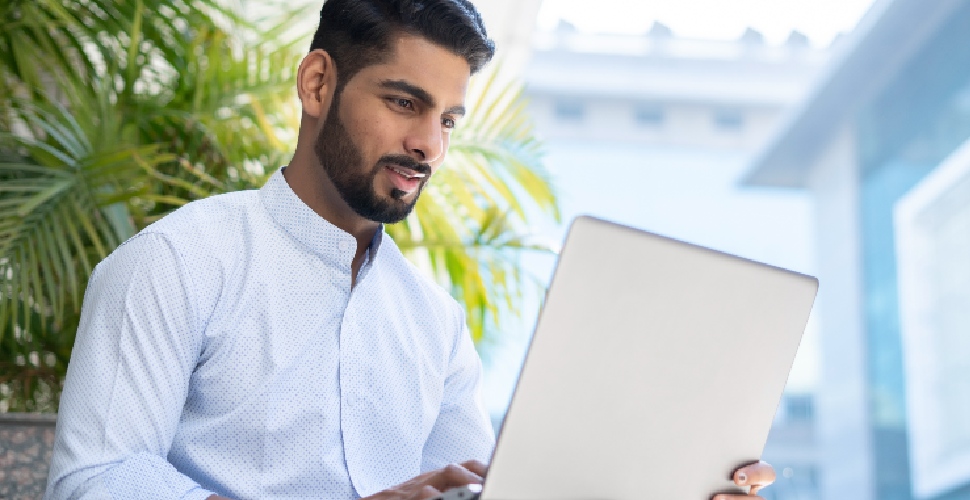 Indian male white-collar professional typing on his laptop.