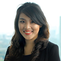 Person smiling against a blurred cityscape background.