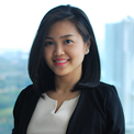 A person smiling in a professional setting with cityscape in the background.