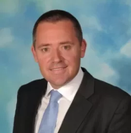 Person in a suit and tie with a blue sky background.