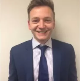 Person in a blue suit and striped shirt smiling at the camera.