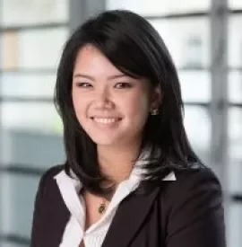 Person smiling in a professional setting, wearing a black suit and white shirt.