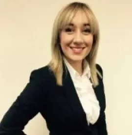 Person smiling in a business suit against a plain background.