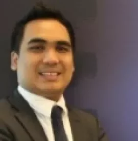 Person smiling in a suit against a purple backdrop.