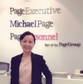 Person smiling at a reception desk with PageGroup signage in the background.