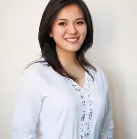 Person smiling in a white lace top against a light background.