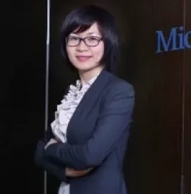 Person in business attire standing with arms crossed in an office.