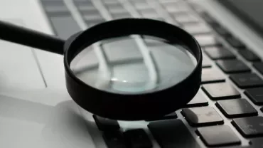 Magnifying glass on a laptop keyboard.