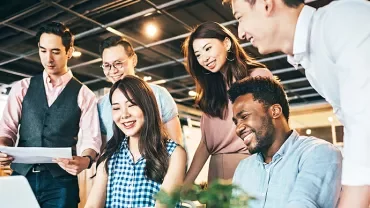 Group of people working together around a laptop.