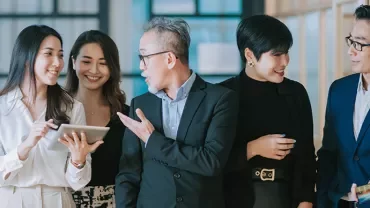 Group of people in an office discussing with a tablet.