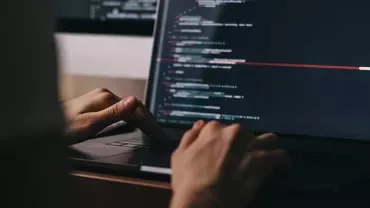 Person coding on a laptop with a dark-themed code editor.