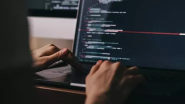 Person coding on a laptop with a dark-themed code editor.