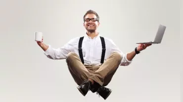 Person balancing laptop and mug while sitting cross-legged.