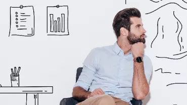 Person sitting in front of a wall with abstract drawings and office sketches.