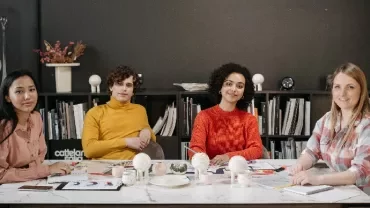 Four people sitting at a table with bookshelves in the background.