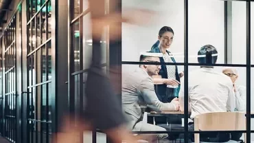 Office team having a meeting in a glass-walled room.