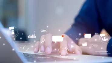 Person typing on laptop with digital icons around.