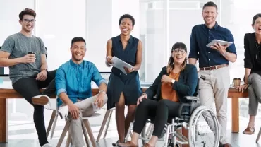 A group of people smiling and sitting in an office setting.