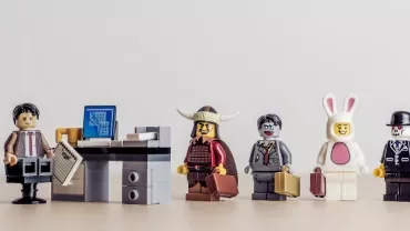 Assorted LEGO figures standing in line next to a desk with a computer.