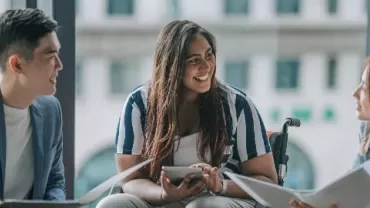 Three people having a discussion in an office setting.