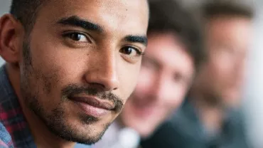 Person in a checkered shirt smiling at the camera.