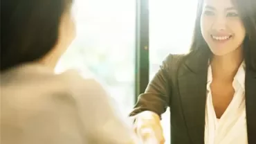 Two people shaking hands in a brightly lit office.