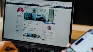 Person using a laptop with a social media profile displayed.
