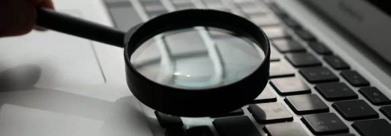 Magnifying glass on a laptop keyboard.