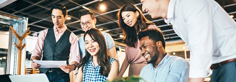 Group of people working together around a laptop.