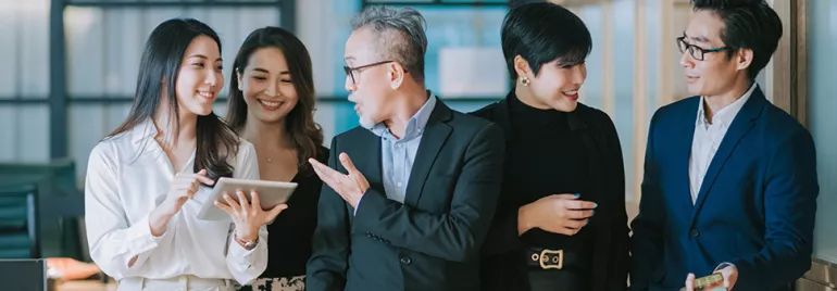 Group of people in an office discussing with a tablet.