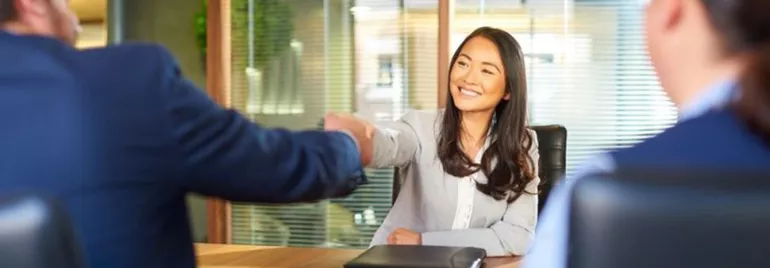 Person smiling and shaking hands in an office meeting.