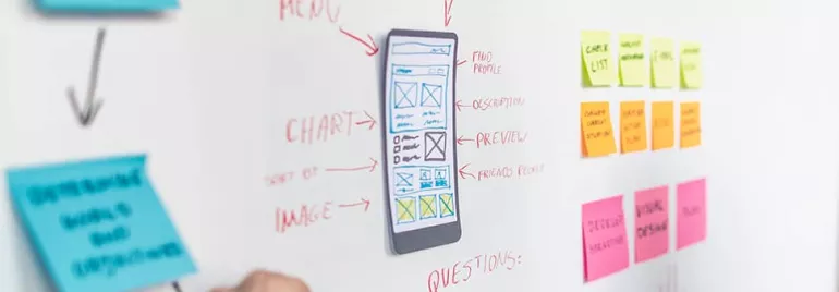 Whiteboard with sketches of a mobile app layout and colorful sticky notes.