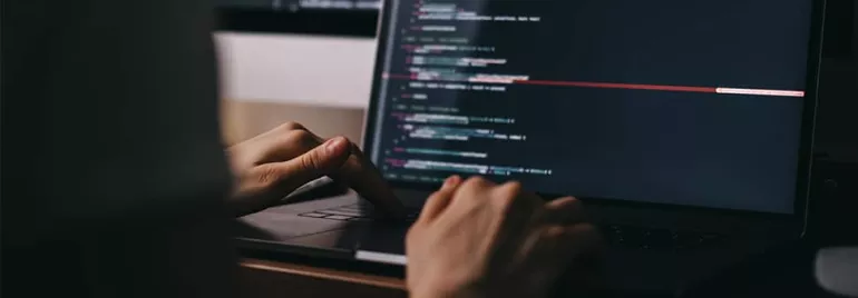 Person coding on a laptop with a dark-themed code editor.