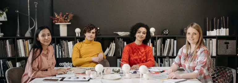 Four people sitting at a table with bookshelves in the background.