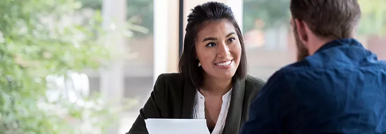 Person smiling in a professional setting during a conversation.
