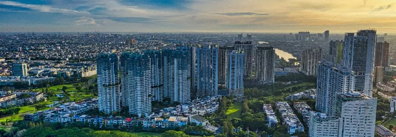 Aerial view of a cityscape with tall buildings and a river under a clear sky.