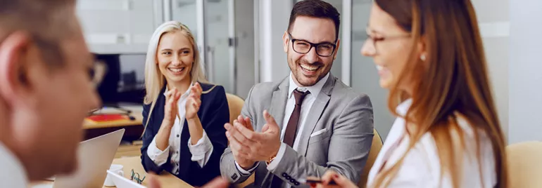 Group of professionals in a meeting, smiling and clapping.