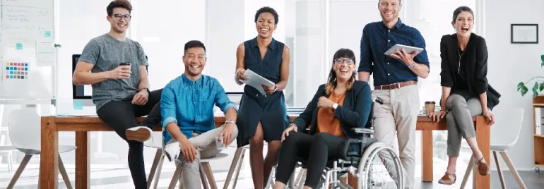 A group of people smiling and sitting in an office setting.