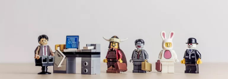 Assorted LEGO figures standing in line next to a desk with a computer.