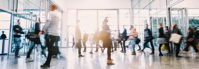 People walking through a busy building entrance, blurred motion.