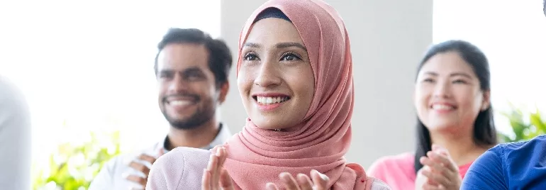 A group of people clapping and smiling at an event.