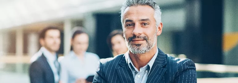 Person in a suit smiling with colleagues in a modern office.