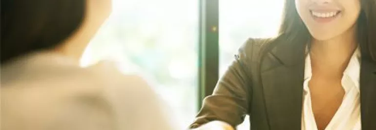 Two people shaking hands in a brightly lit office.