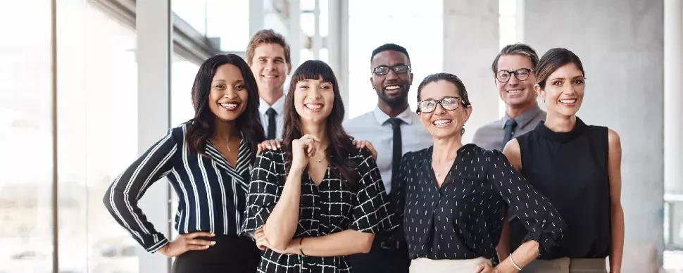A group of smiling professionals in an office setting.