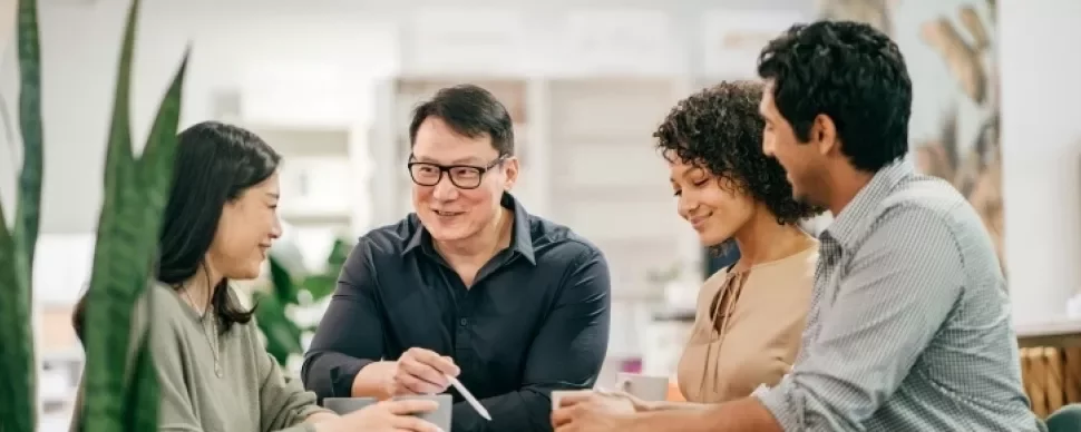 A gathering of people around a table, participating in a discussion and sharing insights in a group setting.