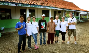 Group of people standing in front of a building with orange roof.