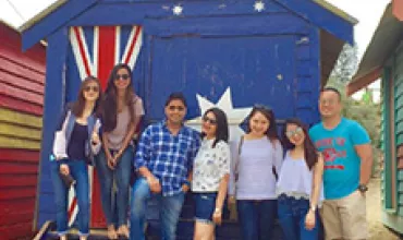 Group posing in front of a beach hut with a flag design.