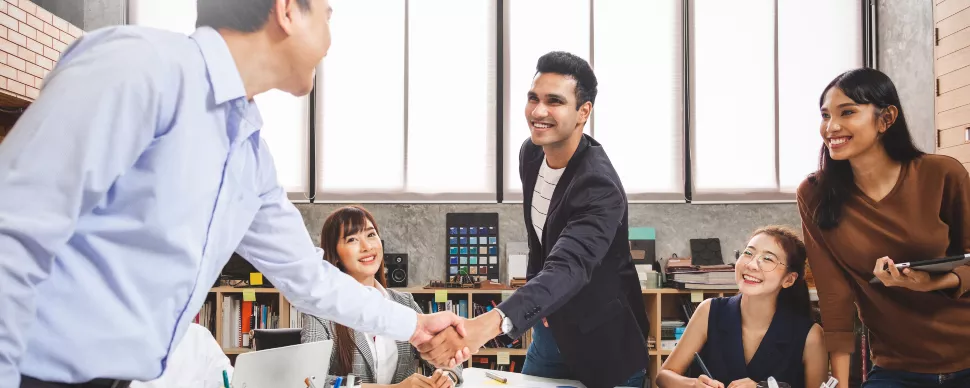 Group of people in an office smiling and shaking hands.