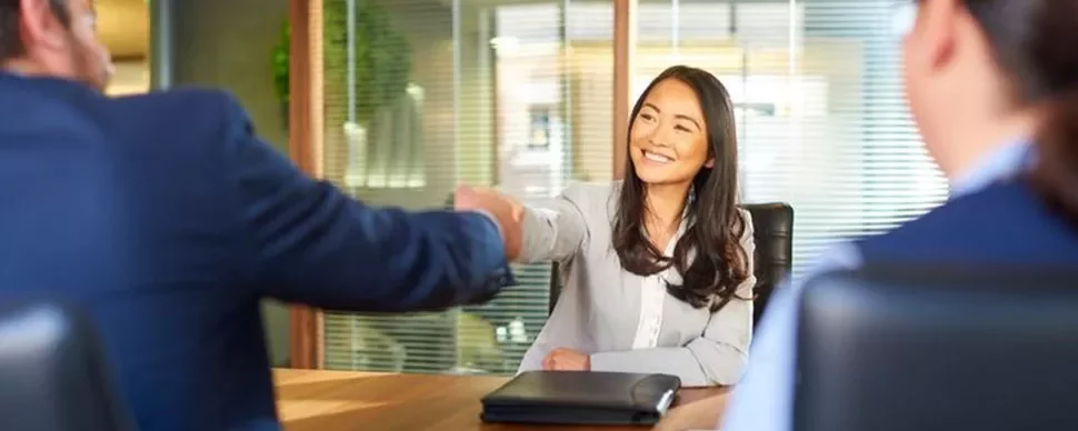 Person smiling and shaking hands in an office meeting.